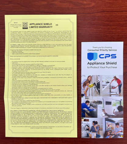 A yellow paper warranty card and a white promotional brochure for CPS Appliance Shield, displayed side-by-side on a dark wood background.