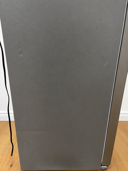 A close-up of a stainless steel refrigerator door, showing the brushed metal surface showing dents.