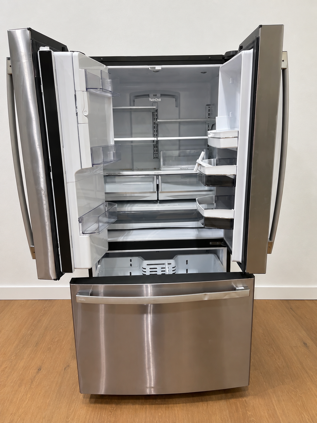 Actual unit with doors open showing the empty interior, TwinChill panel, and adjustable shelves