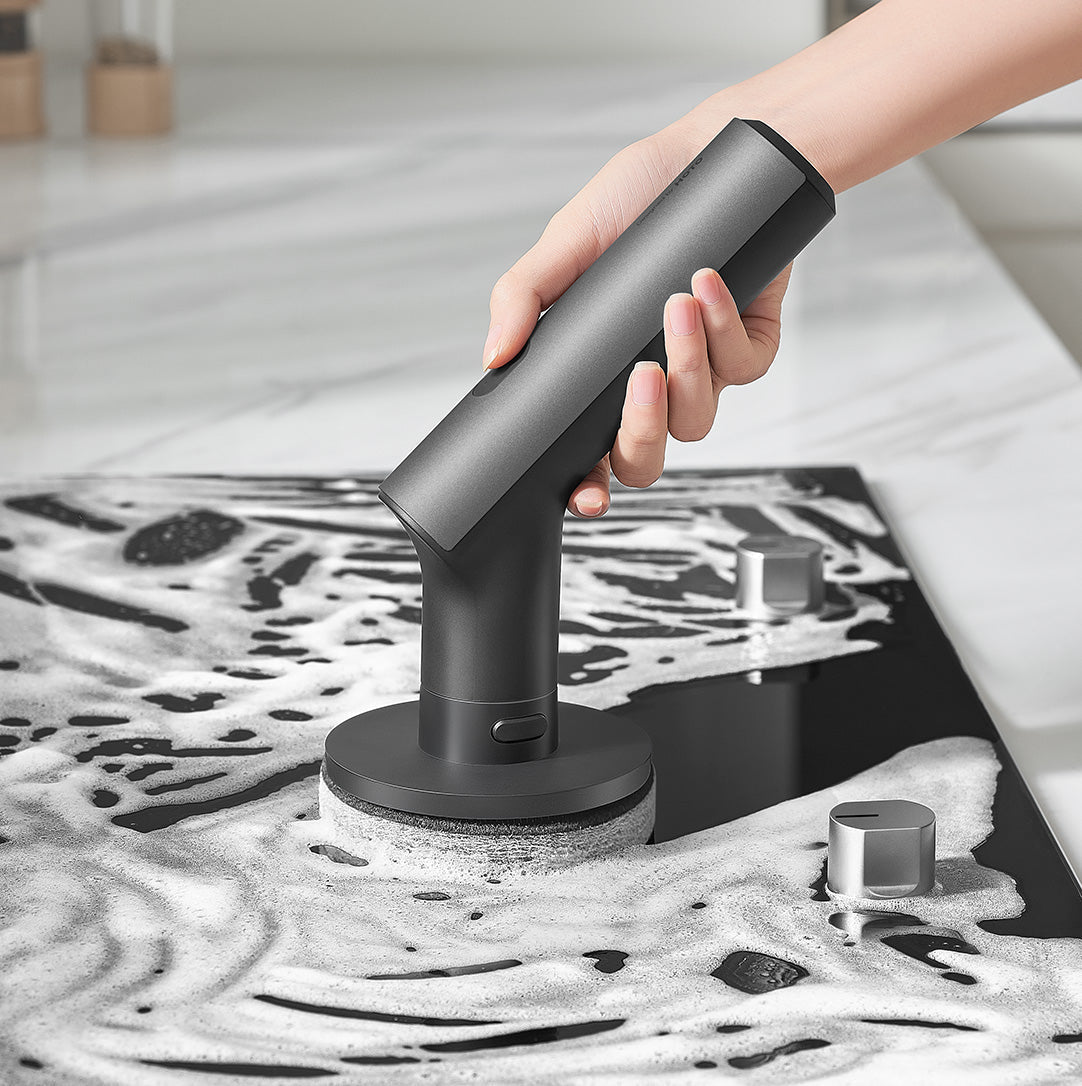 Person using the HOTO Cordless Spin Scrubber to clean a soapy kitchen countertop with the sponge pad attachment