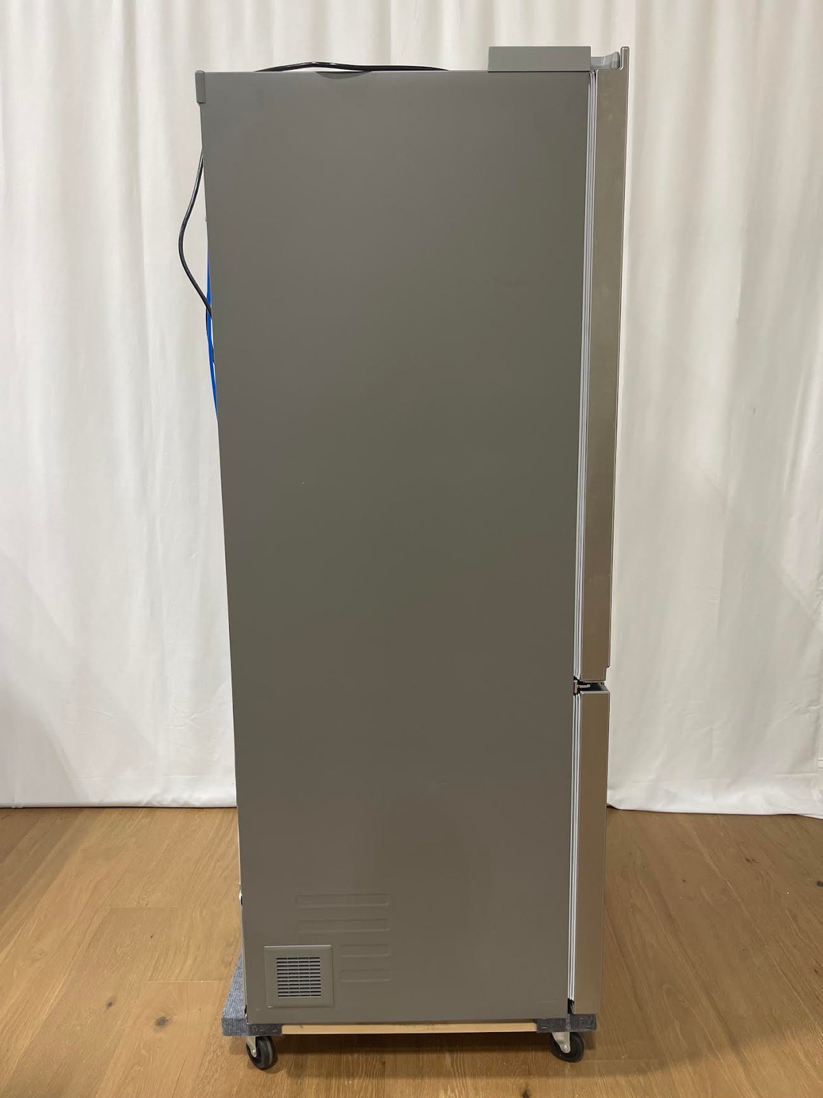 A tall, gray industrial refrigerator or freezer cabinet on casters, shown from the side.
