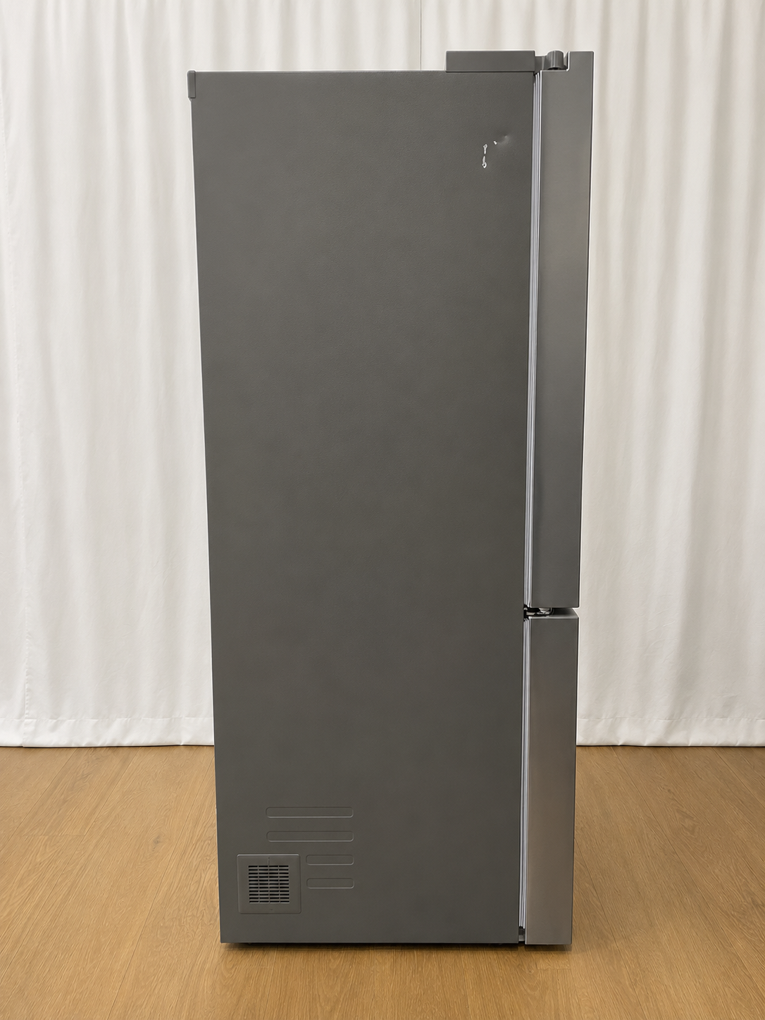 Side view of the refrigerator showing the dark side panel and door hinges