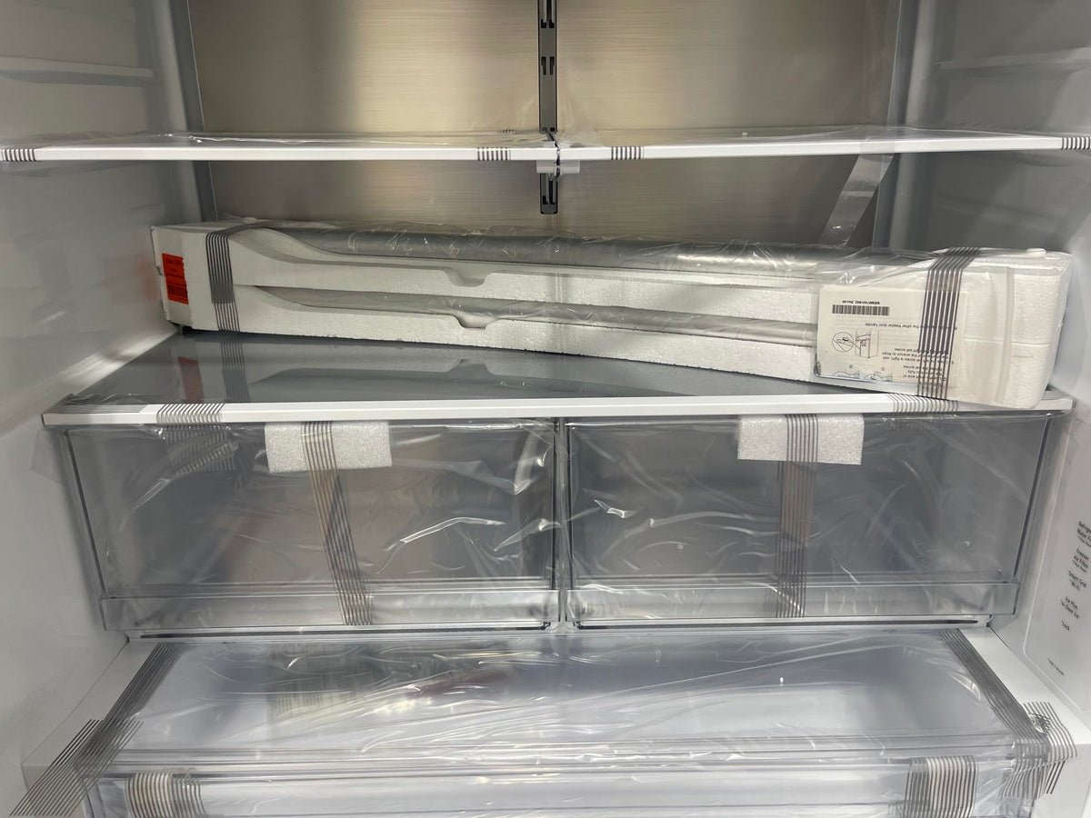 Close-up of the top interior shelf showing a spare freezer door handle accessory box still in factory wrapping, with the control panel label list visible