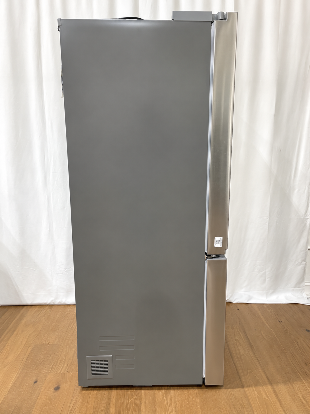 A tall, stainless steel refrigerator with a bottom freezer drawer.