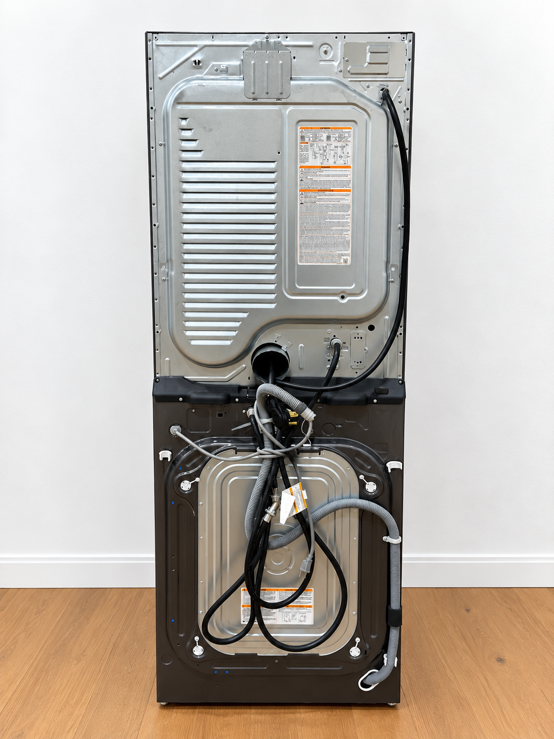 LG WKEX200HBA WashTower rear panel closeup showing power cord, water hoses, and vent connections