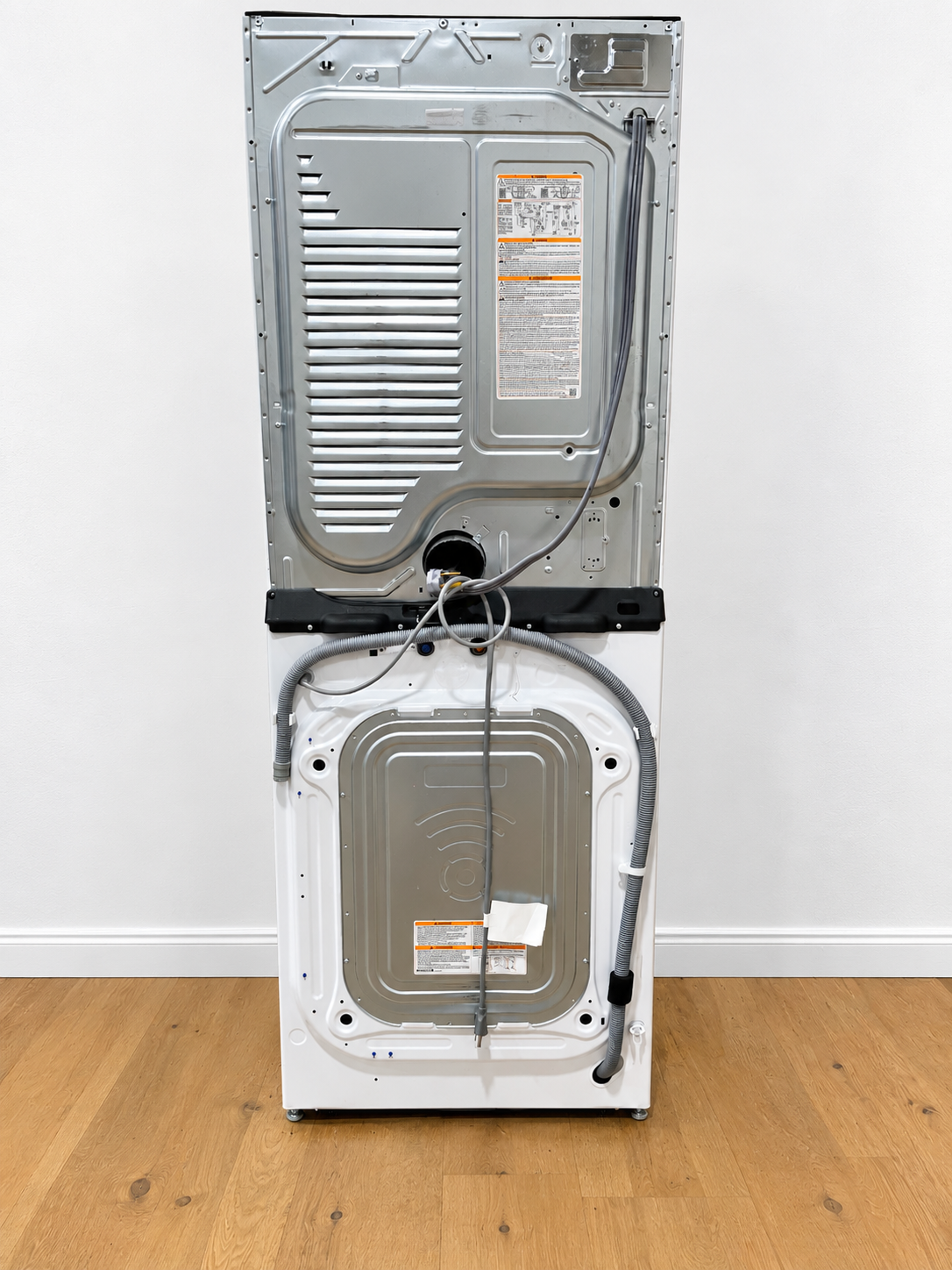 LG WKE100HWA WashTower rear panel showing power cord, water hoses, and vent connections