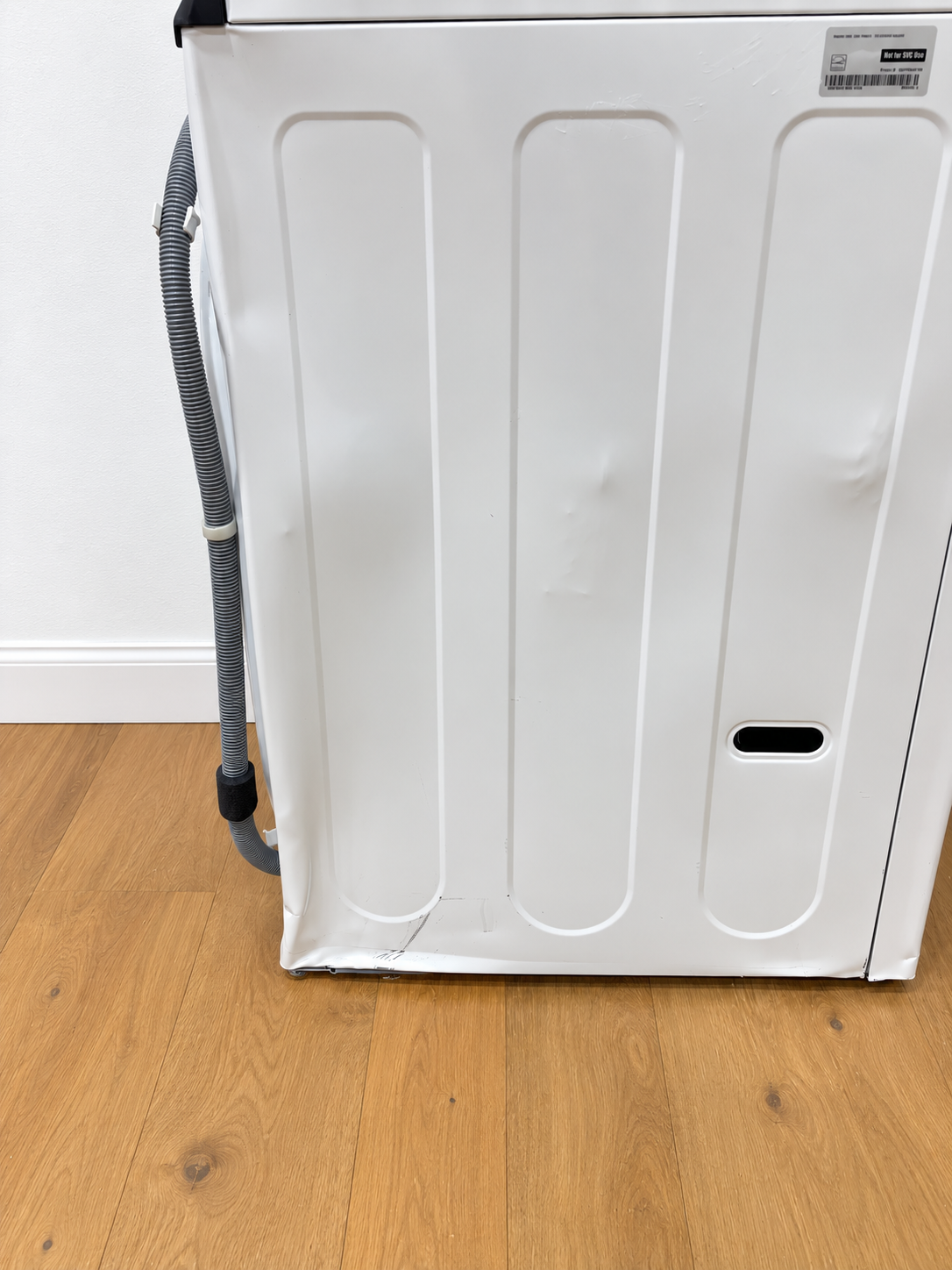 LG WKEX200HWA WashTower closeup of lower unit side panel showing a dent