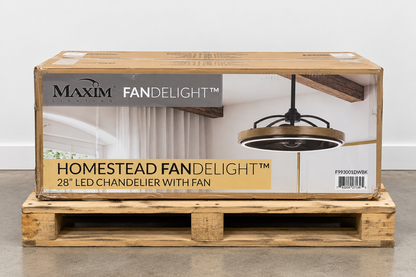 Maxim Fandelight Homestead 28-inch LED chandelier with fan, shown in its original wooden shipping box on a wooden pallet against a white wall.