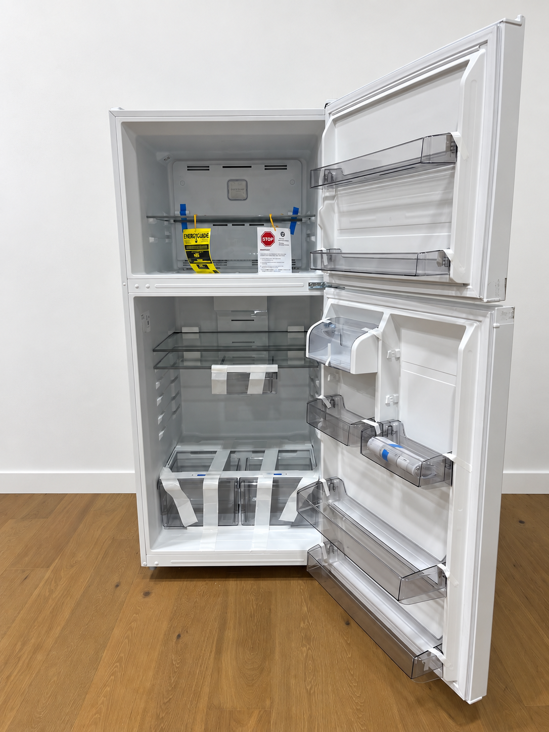 A white top-freezer refrigerator shown with both doors open, revealing the empty interior shelves, door bins, and lower drawer.