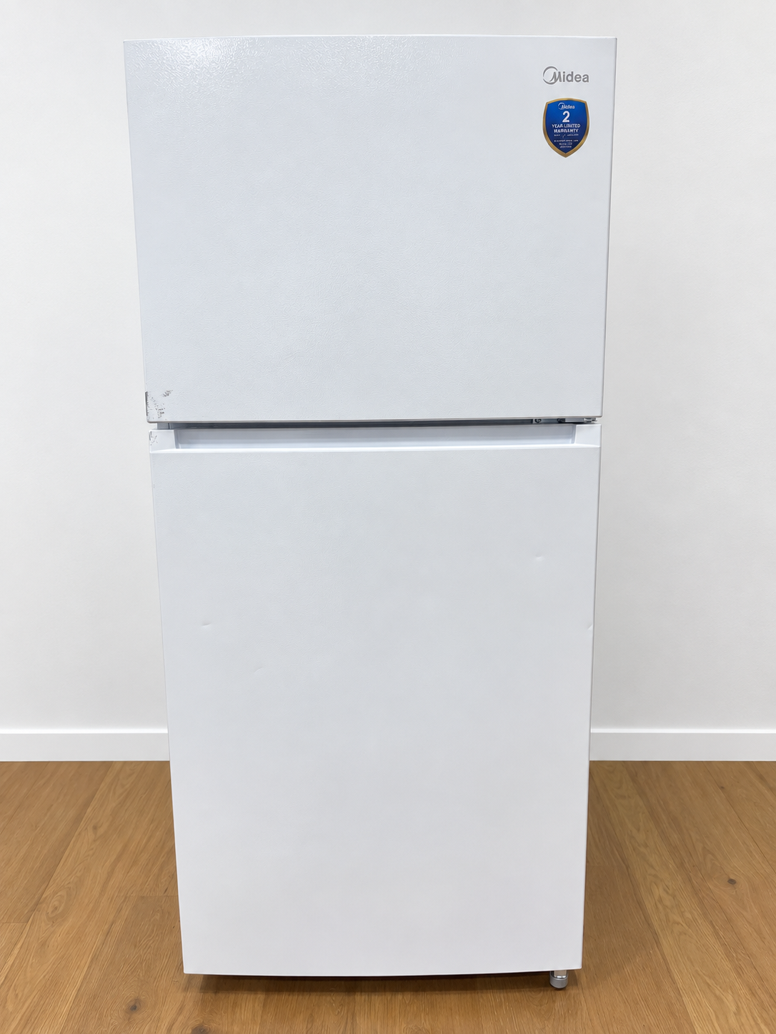 A white Midea top-freezer refrigerator standing.