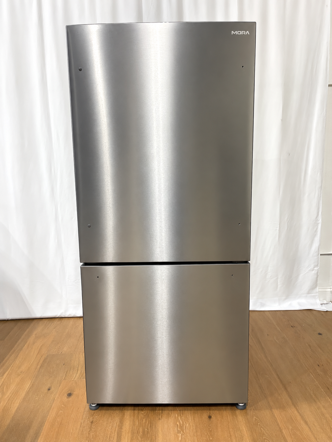A stainless steel top-freezer refrigerator with a small visible Midea logo in the upper right corner.
