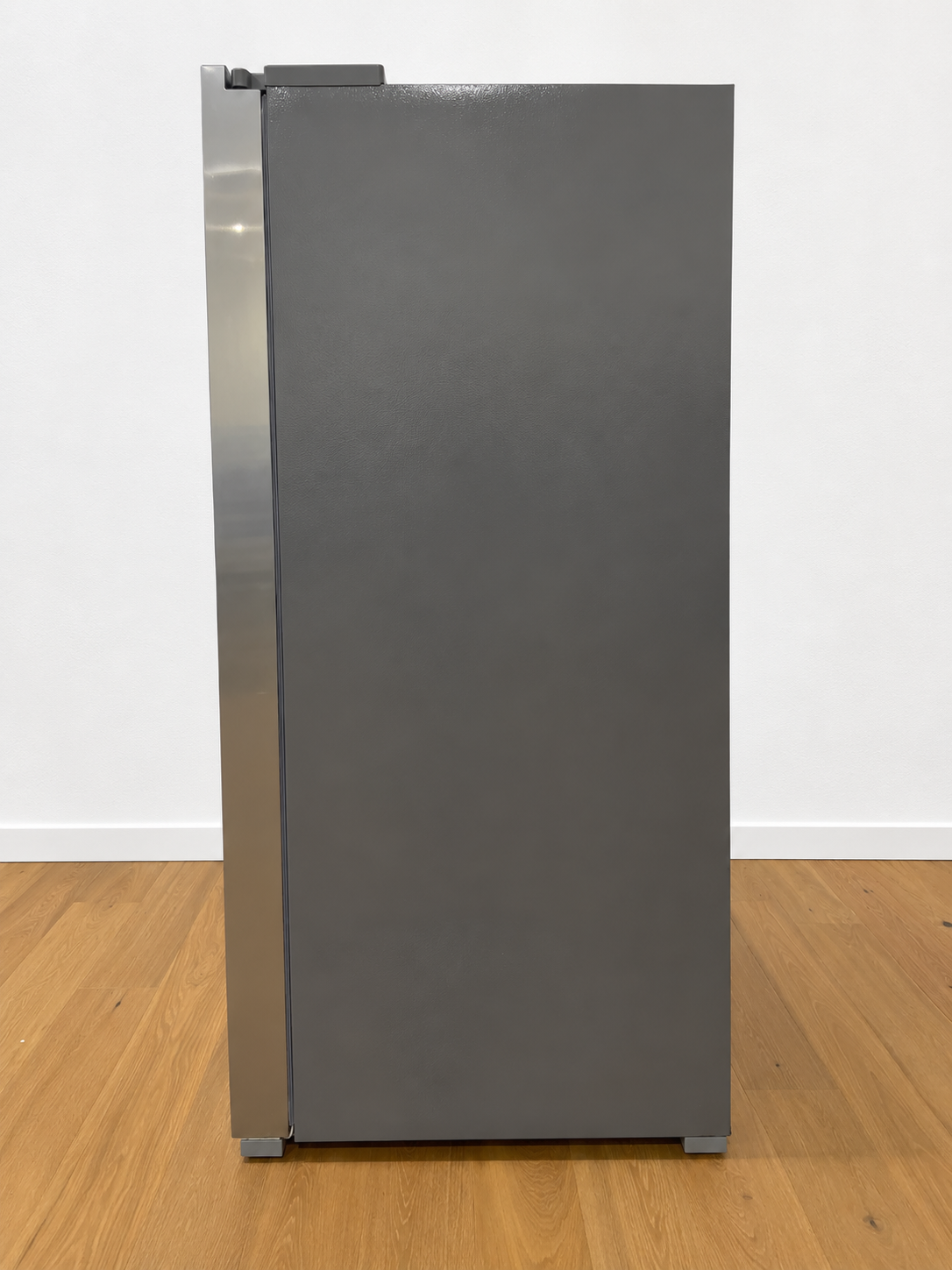 A tall, modern refrigerator with a dark gray front door and brushed stainless steel side panel.