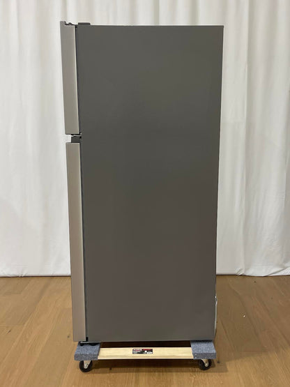 A tall, gray refrigerator with a top freezer compartment, shown standing on a wheeled dolly with a wooden board on a light wood floor in front of a white curtain backdrop.