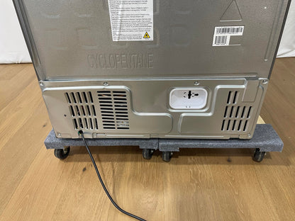 The back view of a stainless steel appliance, likely a refrigerator or freezer, resting on a gray wheeled dolly over a light wood floor.