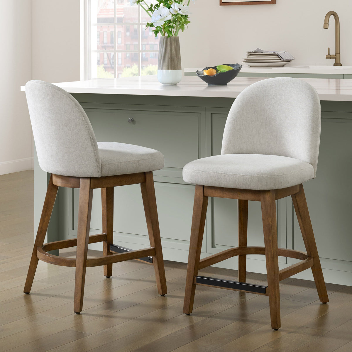 Two Pike & Main Ophelia counter height swivel stools with off-white fabric seats and walnut-tone wood frames at a kitchen island