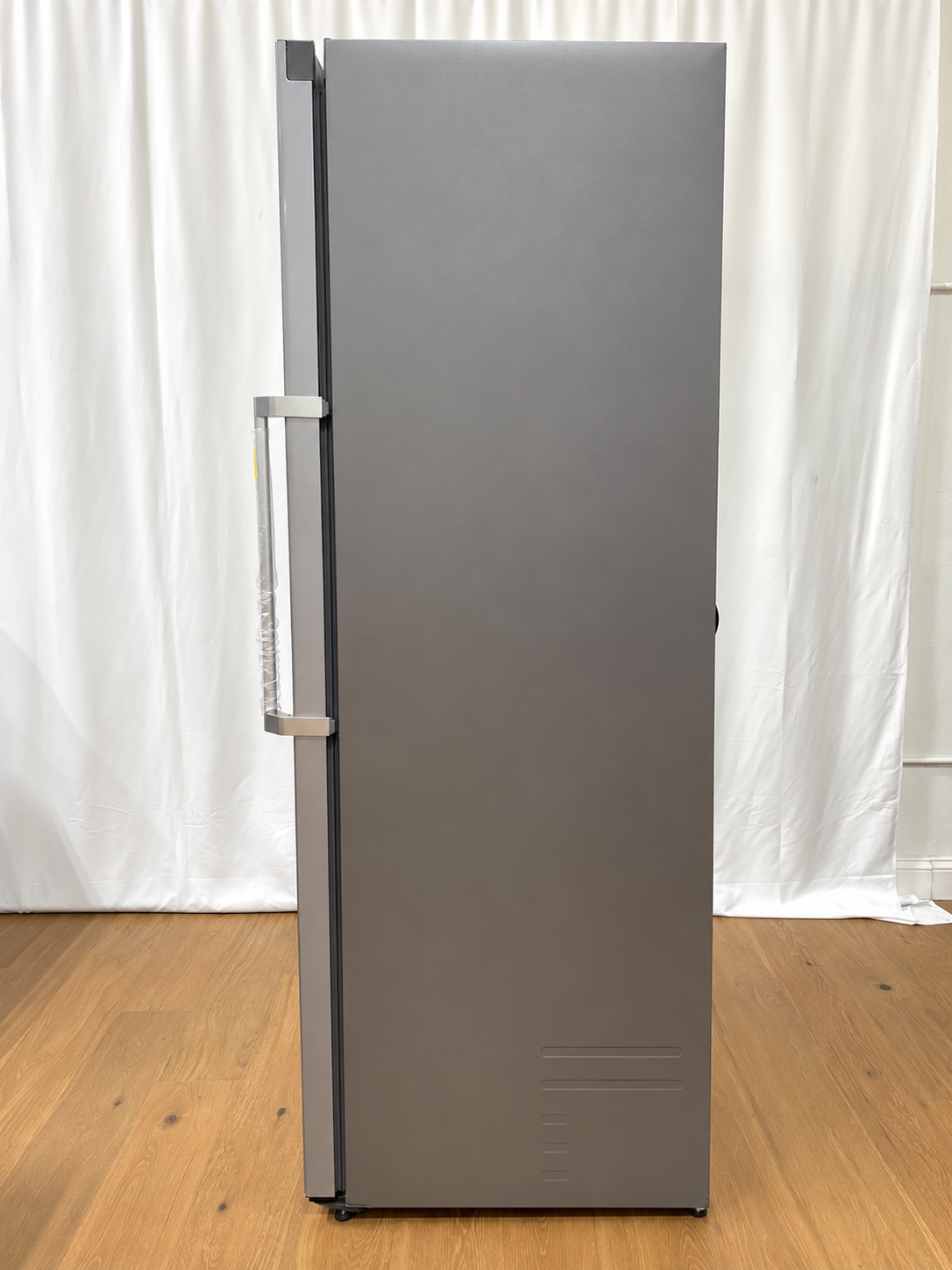 A tall, narrow stainless steel refrigerator with a vertical handle.