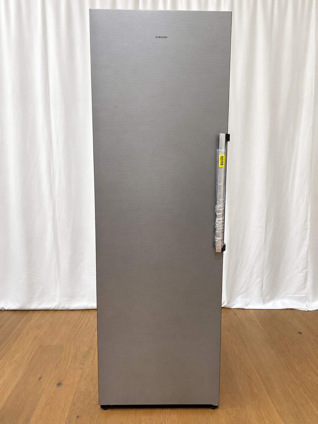 A tall, slim Samsung refrigerator with a brushed stainless steel finish.