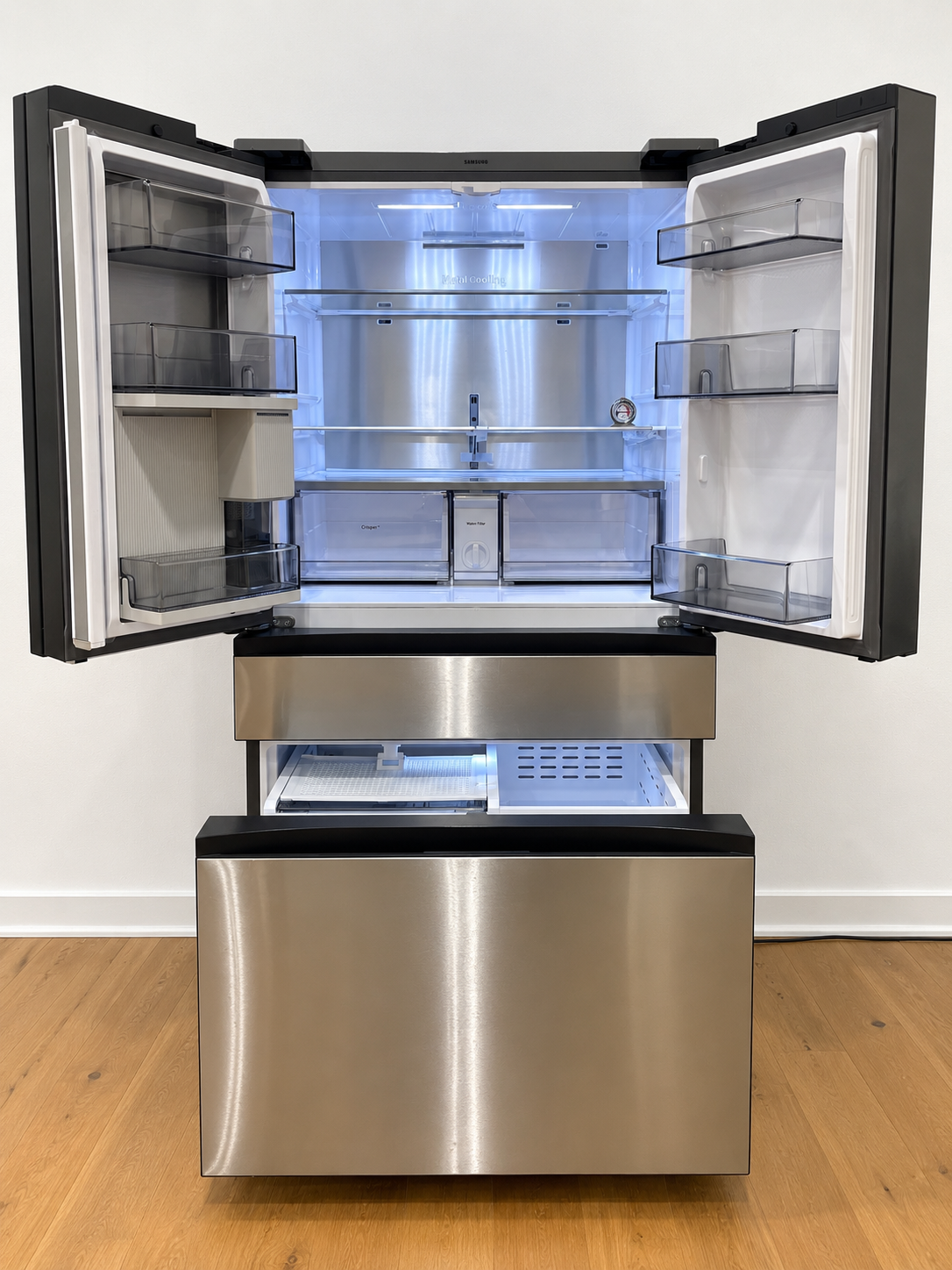 A stainless steel French door refrigerator with both upper doors open, showing the interior shelves and light.